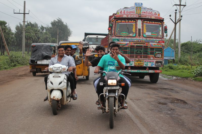 Motorcycles, a three-wheeled vehicle and a decorated truck on a road during an India mission trip