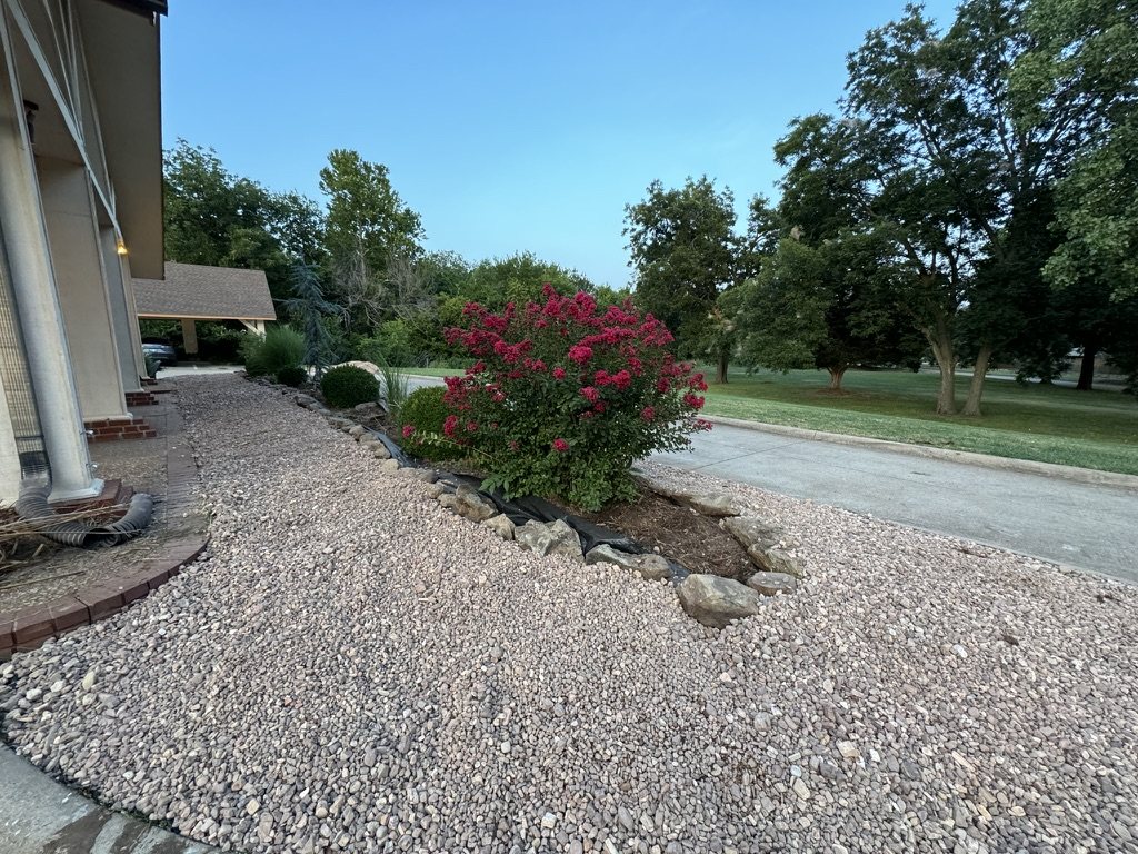 Rock groundcover and stone-edged planting beds with flowering shrubs at Christian Villa