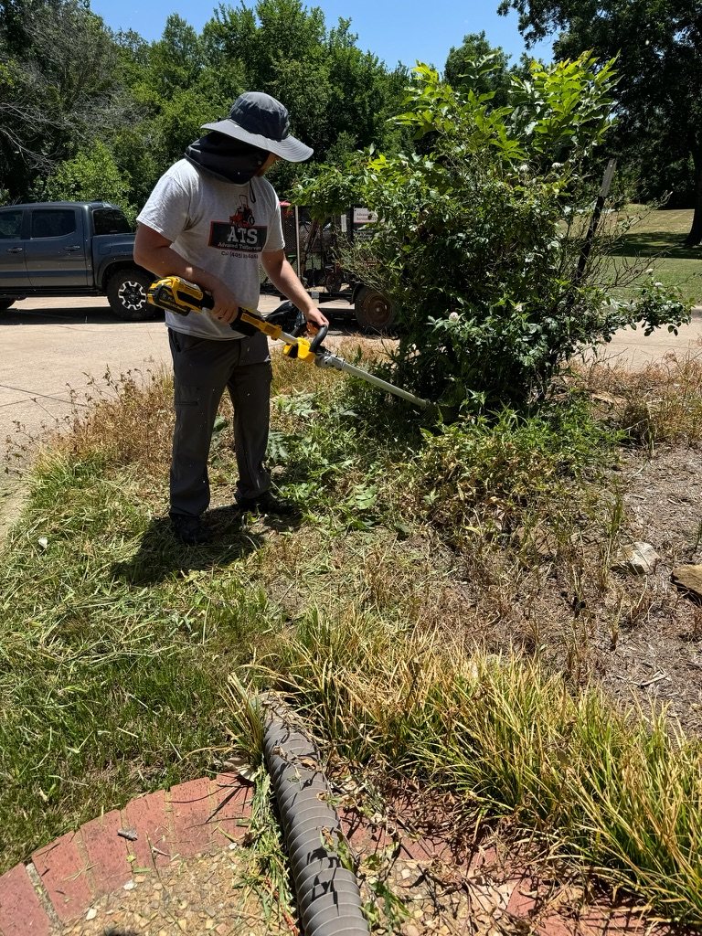 Shrub trimming in progress beside a residential landscape bed