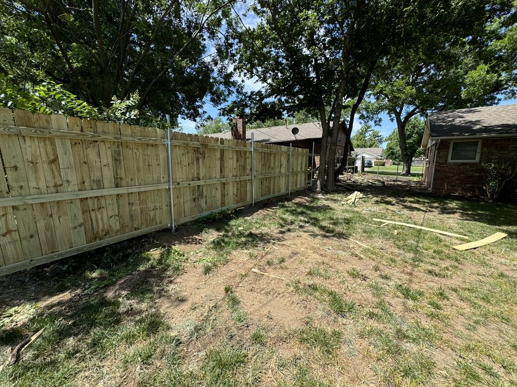 Wood privacy fence supported by round metal posts, viewed from inside the yard
