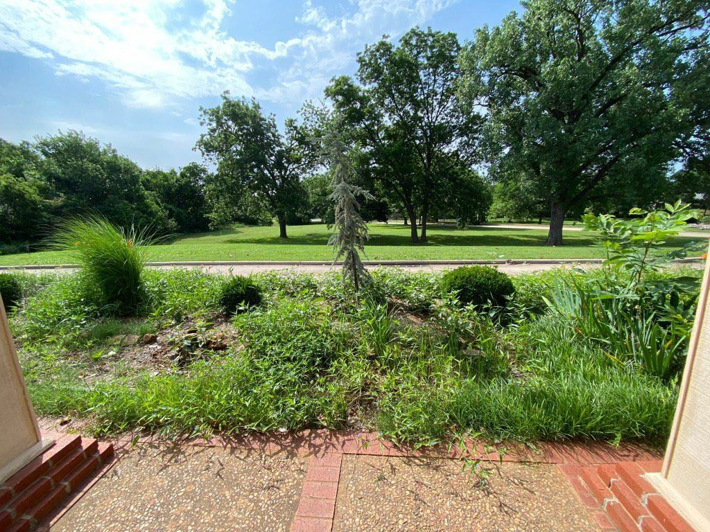 Overgrown shrubs and planting beds before landscape maintenance at Christian Villa
