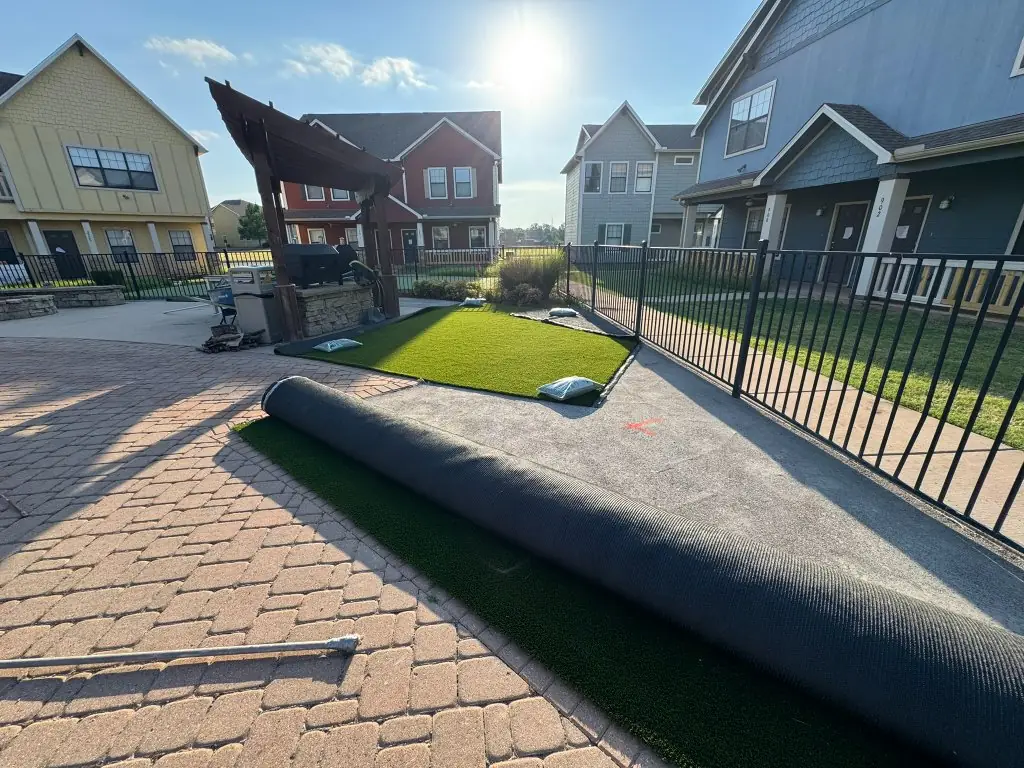 Artificial turf installation in progress beside the pergola and pavers at Cottage Row