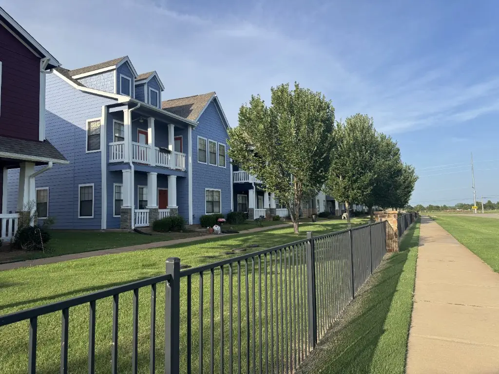 Black metal fence beside a residential lawn and sidewalk