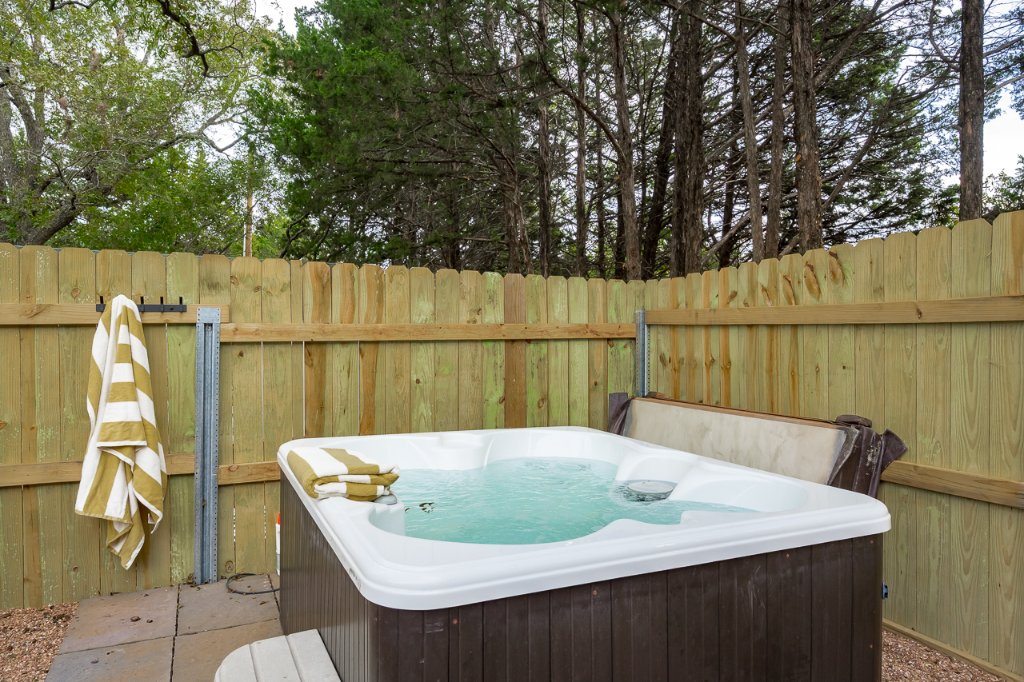 Hot tub on a paved pad beside gravel groundcover and wood privacy fencing