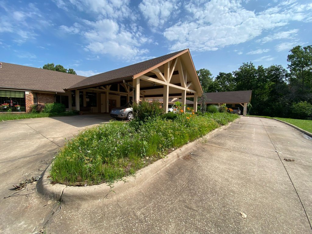 Overgrown planting beds at the Christian Villa entrance before landscape renovation