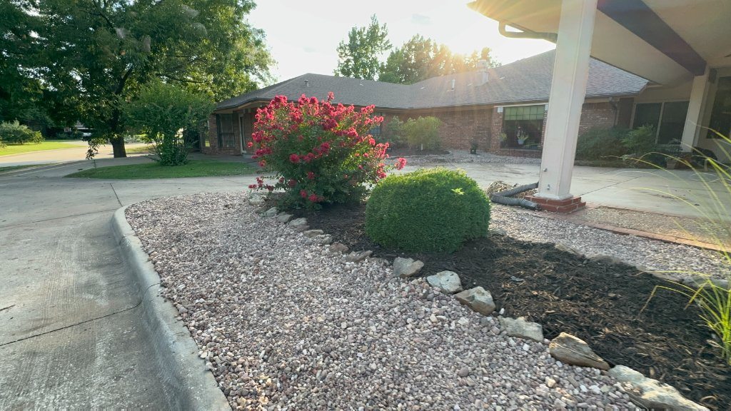 Flowering shrubs and trimmed plants in rock-covered beds beside Christian Villa