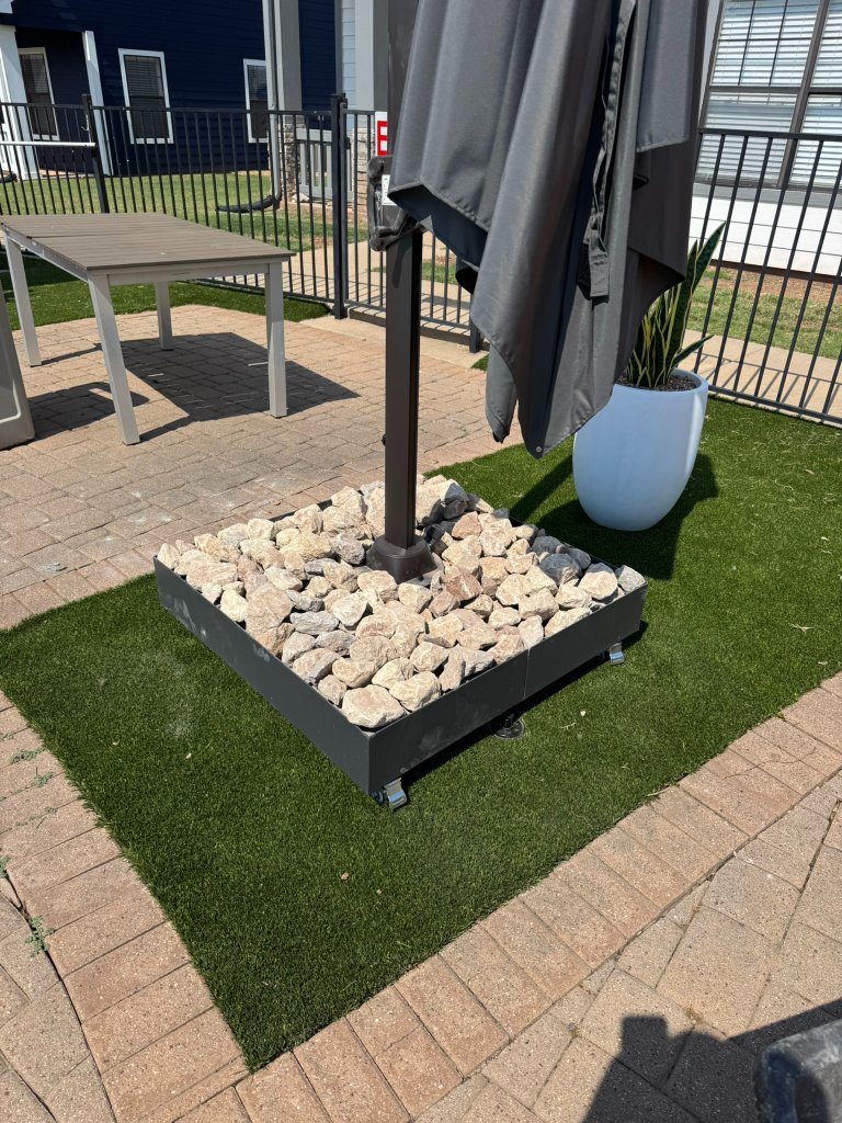 Small tree in a stone-filled bed surrounded by artificial turf at Cottage Row