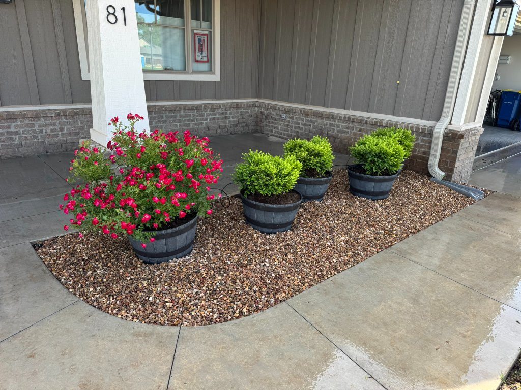 Flower-filled pots on decorative gravel beside a front porch